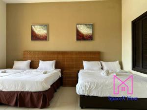 万津Gold Coast Morib Resort的两张睡床彼此相邻,位于一个房间里