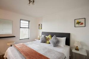 开普敦Rondebosch Central的白色卧室配有带枕头的大床