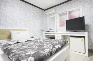 大邱城市之梦汽车酒店的一间卧室配有一张床和一张书桌及电视