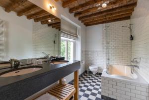 巴尔洛Fletcher Hotel Château De Raay的一间带两个盥洗盆、浴缸和卫生间的浴室