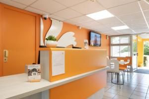 勒河畔的圣马丁Première Classe Châlons-en-Champagne的一间拥有橙色墙壁和前台柜台的办公室