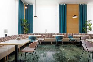 昆卡NH昆卡城市酒店的餐厅设有桌椅和蓝色窗帘