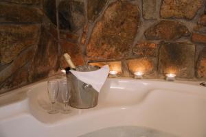 帕莱斯潘蒂雷蒙Pliades Traditional Guesthouse的浴缸配有桶、玻璃杯和蜡烛