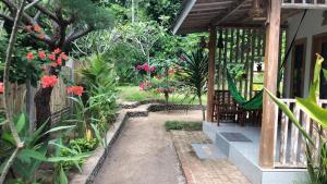 PawenangBale Kebon Rangsot的鲜花花园和带吊床的门廊