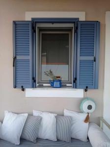 Seaside resort- kallithea的配有蓝色百叶窗的窗户和配有枕头的沙发