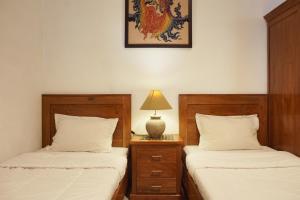 日惹RedDoorz at Griya Cemara Homestay Yogyakarta的一间卧室配有两张床和床头灯。
