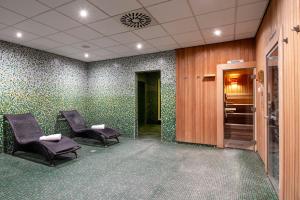 安特卫普安特卫普皇冠假日酒店的一间等候室,配有两把椅子和绿色壁纸