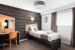 阿勒浦加里东尼亚订制酒店的酒店客房配有一张床、一张书桌和一张书桌。