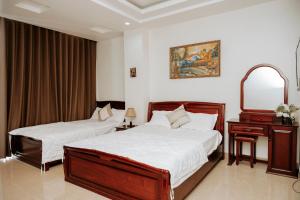 海防Thao Vy Hotel的一间卧室配有两张床、一个梳妆台和镜子