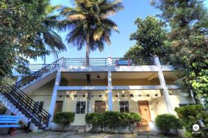 马迪凯里Coorg Avani Holiday Inn的阳台上有一棵棕榈树的房子