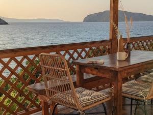 依拉佩特拉Santa Maria - Seaside Serenity的俯瞰水面的甲板上的木桌和椅子