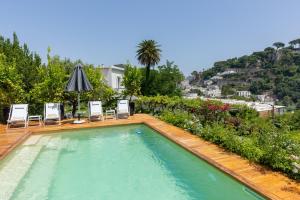 卡普里Villa La Pergola Capri的一座带椅子和遮阳伞的游泳池