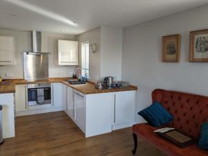 特维德上游的贝里克18 Mill Wharf Apartment的厨房配有白色橱柜和红色沙发