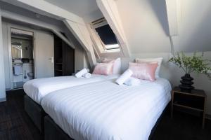 阿姆斯特丹马尔塔图里酒店的卧室配有2张带粉色和白色枕头的床