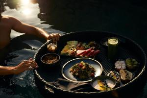 阿基欧斯尼古拉斯米诺斯宫套房酒店 - 仅限成人入住的水中的人,带食物的桌子