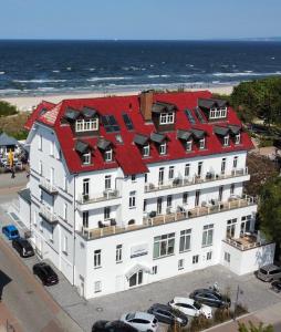 塞巴特阿尔贝克Strandhotel Ostende的一座大型白色建筑,在海边设有红色屋顶