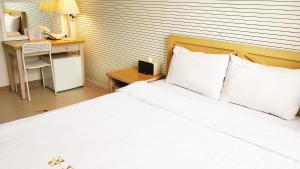 济州市金园酒店的卧室配有一张白色的床、一张桌子和一张书桌。