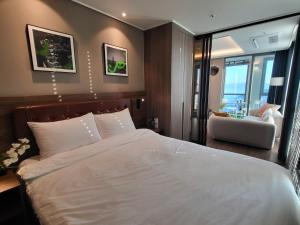 釜山ELBON the stay Haeundae beach的卧室配有一张白色大床和一把椅子