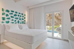 Kyra PanagiaEnilion Luxury Suites的白色卧室设有一张大床和一个滑动玻璃门