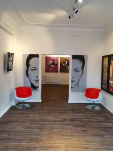 不莱梅artHOTEL Bremen的一间房间,墙上挂着两把红色椅子和绘画作品