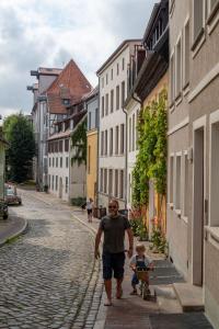 罗斯托克Über den Dächern der Altstadt的跟孩子在车上走下街的人