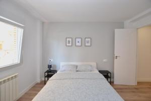 奥维多STAY Las Segadas的一间白色卧室,配有一张床和两张桌子