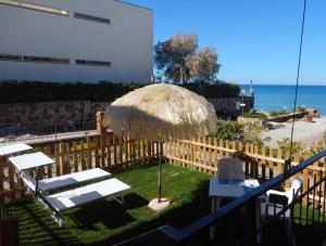 圣温琴佐Ville Paola e Daniela的一个带稻草伞和椅子的庭院,享有海景