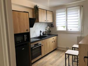 兰斯Camden - Extérieur et parking的厨房配有木制橱柜和黑色冰箱。