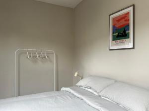 哈罗盖特Strawberry Dale Apartment的白色的卧室配有一张床,墙上挂着一幅画