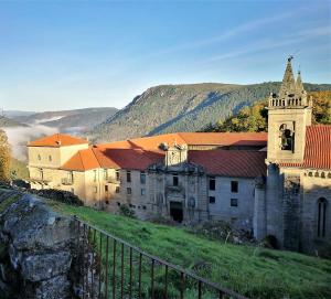 RubiacósLa Casa de las rocas - Ribeira Sacra的一座位于山丘上的古老建筑,背景是群山