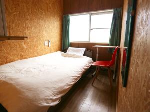立山町立山沃斯旅馆的一间小卧室,配有一张床和一把红色椅子