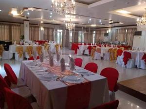 杜马格特Aberrise Country Villa Pension Hotel的一个带白色桌子和红色椅子的大型宴会厅