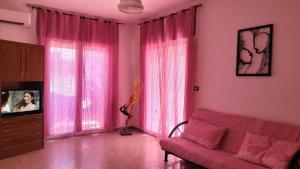 布林迪西Casa Vacanza Casale的客厅配有粉红色窗帘和沙发