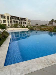 马斯喀特Jebel Sifah Golf View Apartment的大楼前的大型蓝色游泳池