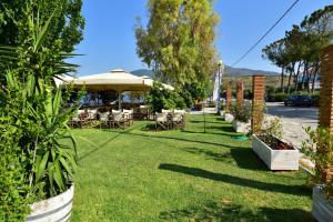 鲁维斯Zagas Hotel Ξενοδοχειο Ζάγκας的花园配有桌椅和遮阳伞。