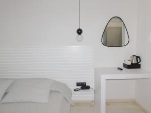 纳乌萨Fotilia Hotel的白色卧室配有床和镜子