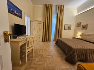 佛罗伦萨Resort del Roster的酒店客房配有一张床、一张书桌和一台电视。