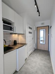 华沙Irisapart A65的厨房配有白色橱柜、水槽和窗户。