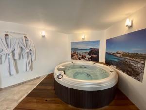 波尔多Mieuxqualhotel jacuzzi privatif Le rond的浴室设有按摩浴缸,墙上挂有绘画作品