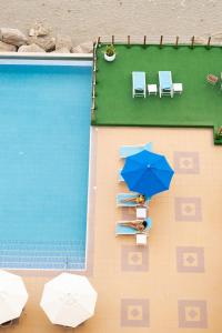曼塔曼塔霍斯特酒店的坐在游泳池旁的蓝色伞下的人