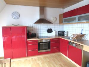 卡尔夫Ferienwohnung Nadine的一间厨房,里面装有红色橱柜,墙上挂着一个时钟