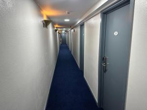 布鲁塞尔Hotel EUROPACITY的一条长长的走廊,铺着蓝色的地毯,设有一扇门