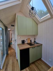 亚斯塔尔尼亚Tiny House Jastarnia的厨房配有绿色橱柜和天窗