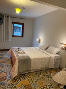 马卡埃Pousada Lazúli的一间卧室设有一张大床和一个窗户。
