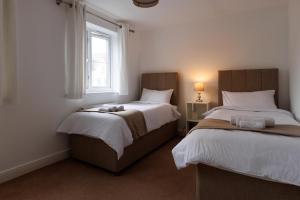 艾尔斯伯里Comfortable 4-Bedroom Home in Aylesbury Ideal for Contractors Professionals or Larger Families的一间卧室设有两张床和窗户。