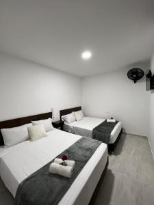 OcañaHotel el tamaco的配有白色墙壁的酒店客房内的两张床