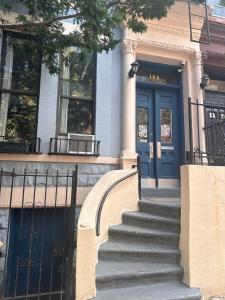 纽约Macaw Guest House的前方有蓝色门和楼梯的建筑