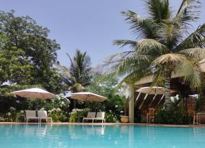 恩加帕鲁La Maison Vanille的一个带遮阳伞和椅子的游泳池以及棕榈树