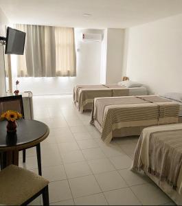 大坎皮纳Majestic Hotel的酒店客房设有三张床和一张桌子