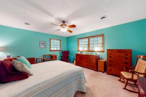 派恩诺尔肖尔斯Pine Knoll Nest的一间卧室设有蓝色的墙壁和一张带吊扇的床。